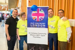 Four people standing around a Sports Fair banner