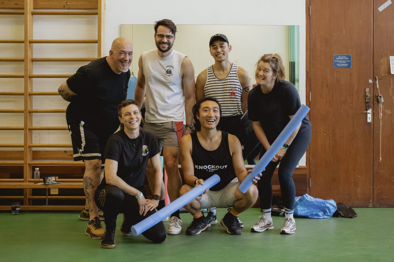 Six smiling members of Knockout Boxing Club in a group photo, part of London’s LGBTQ+ sports community.